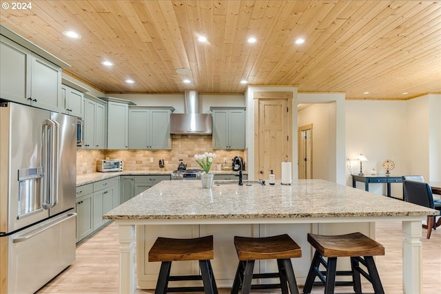 kitchen with light stone countertops, wood ceiling, high quality fridge, and wall chimney exhaust hood