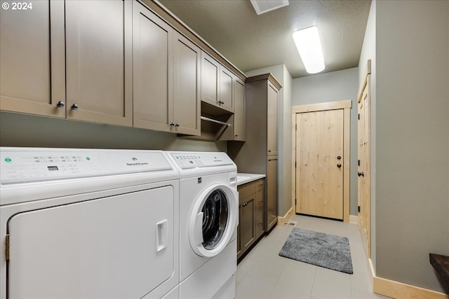 laundry area featuring washer and clothes dryer, cabinets, and a textured ceiling