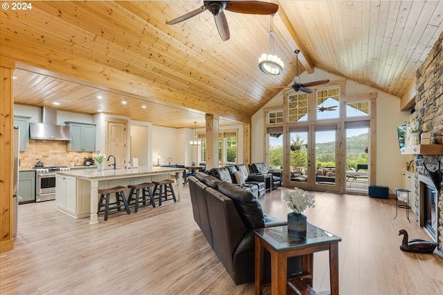 living room featuring high vaulted ceiling, wooden ceiling, beamed ceiling, a fireplace, and light hardwood / wood-style floors