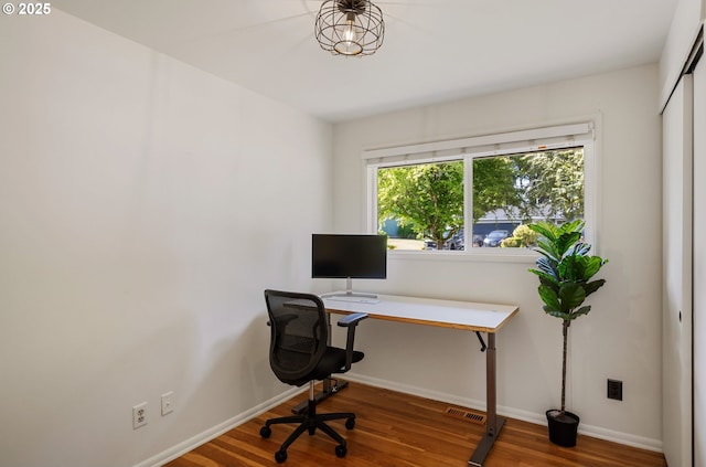 office space with baseboards, wood finished floors, and visible vents