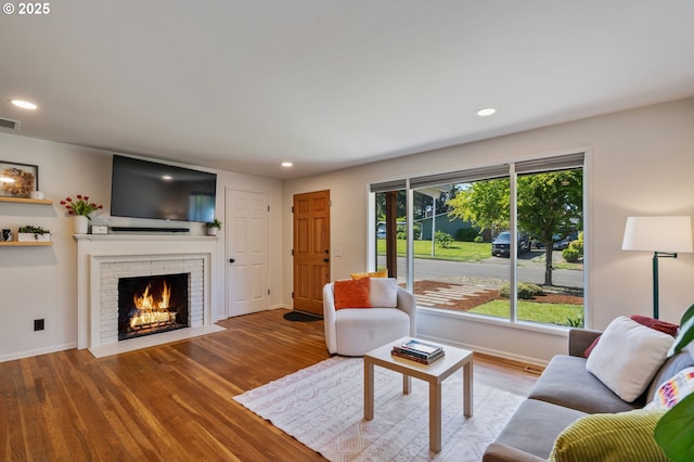 living area with recessed lighting, baseboards, wood finished floors, and a fireplace
