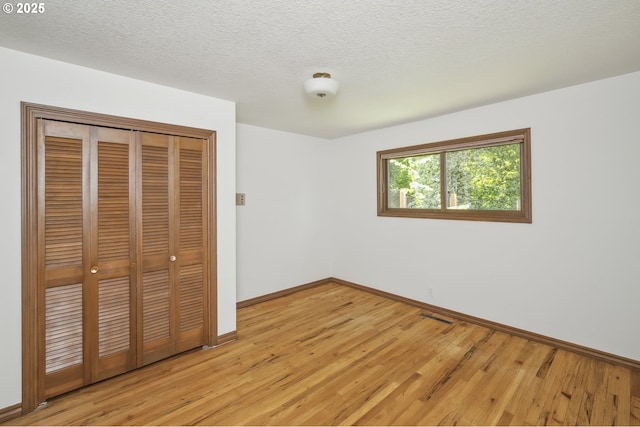 10776 SE Idleman Rd, Happy Valley, OR 97086 - unfurnished bedroom featuring light wood-style floors, baseboards, a closet, and a textured ceiling