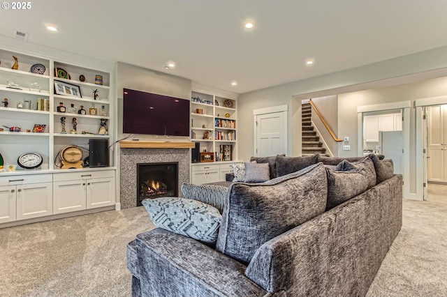 living room with light colored carpet, visible vents, a warm lit fireplace, and recessed lighting