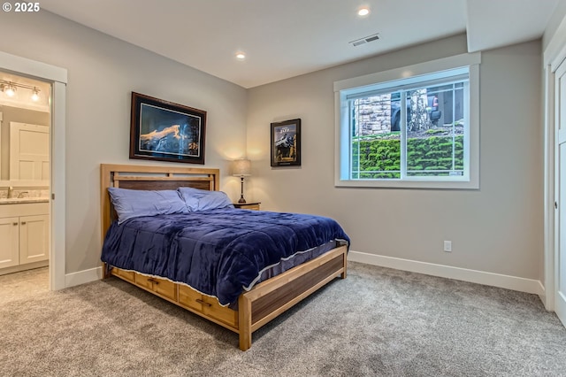 bedroom featuring a sink, light carpet, baseboards, and visible vents