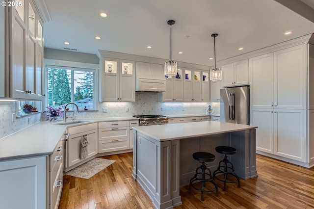 kitchen with light wood finished floors, appliances with stainless steel finishes, a center island, and a sink