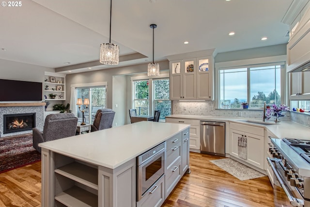 kitchen featuring light countertops, a glass covered fireplace, appliances with stainless steel finishes, and a sink