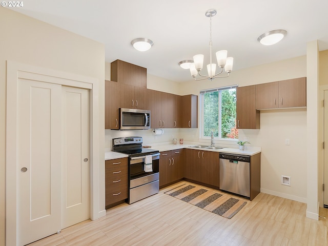 kitchen with appliances with stainless steel finishes, a chandelier, sink, and hanging light fixtures