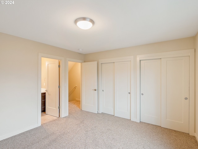 unfurnished bedroom with light carpet and two closets