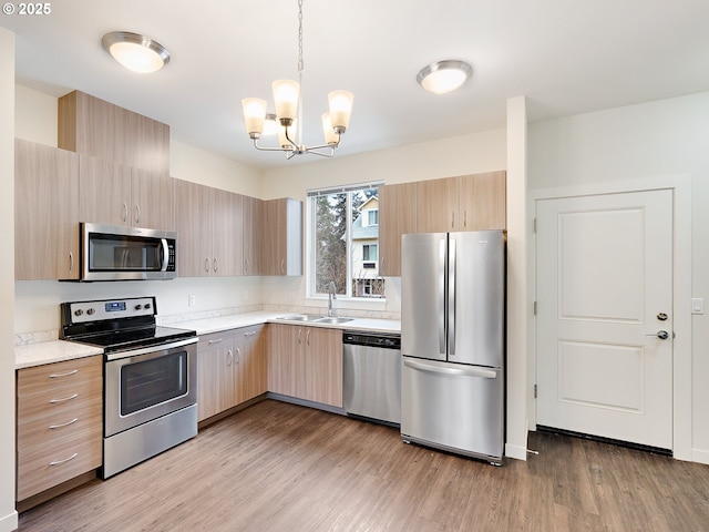 10829 E Burnside St, Portland, OR 97216 - kitchen with appliances with stainless steel finishes, a sink, light wood finished floors, a chandelier, and light brown cabinets
