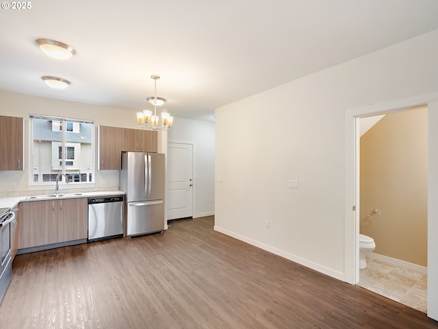10829 E Burnside St, Portland, OR 97216 - kitchen with stainless steel appliances, a sink, light countertops, light wood-type flooring, and a chandelier