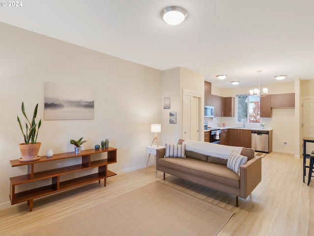 living room featuring a notable chandelier, sink, and light wood-type flooring