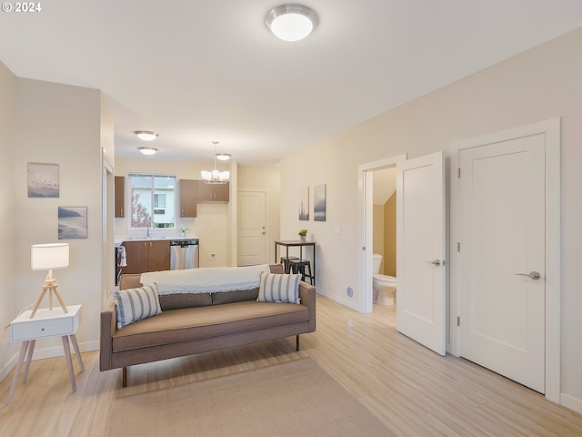 bedroom featuring connected bathroom, sink, light hardwood / wood-style flooring, and a notable chandelier