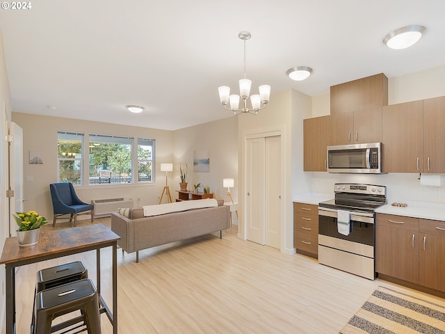 kitchen featuring stainless steel appliances, decorative light fixtures, a chandelier, and light wood-type flooring