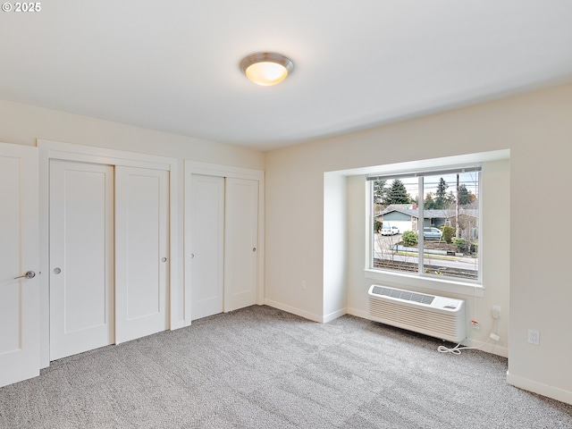 10829 E Burnside St, Portland, OR 97216 - unfurnished bedroom featuring multiple closets, carpet, baseboards, and a wall unit AC