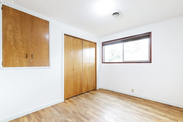 7430 N Burr Ave, Portland, OR 97203 - unfurnished bedroom featuring light wood-style floors, baseboards, a closet, and a textured ceiling