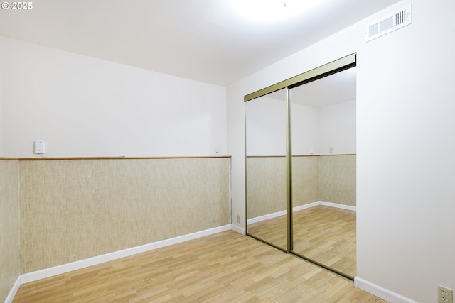7430 N Burr Ave, Portland, OR 97203 - unfurnished bedroom featuring wood finished floors, a wainscoted wall, baseboards, and a closet