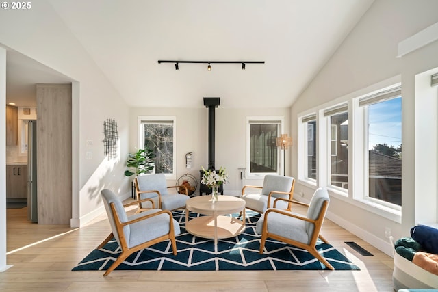 90 Beach Dr, Manzanita, OR 97130 - dining space featuring track lighting, a wood stove, vaulted ceiling, and light wood-style floors
