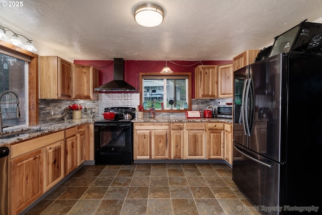 kitchen featuring sink, tasteful backsplash, light stone counters, wall chimney range hood, and stainless steel appliances