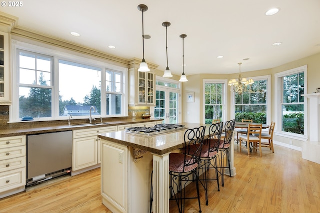 kitchen featuring decorative backsplash, dishwashing machine, a kitchen breakfast bar, stainless steel gas stovetop, and a sink