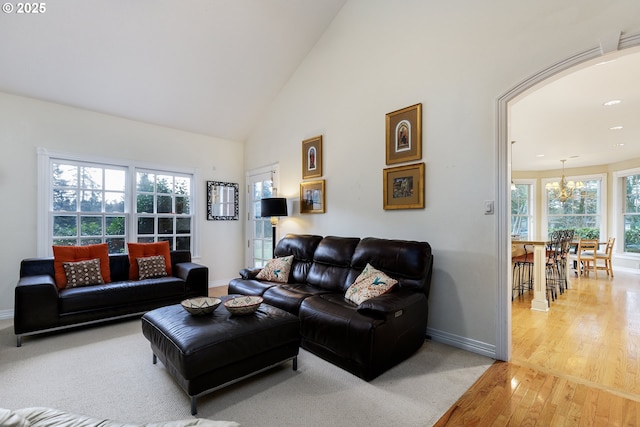 living room with light wood finished floors, baseboards, and high vaulted ceiling