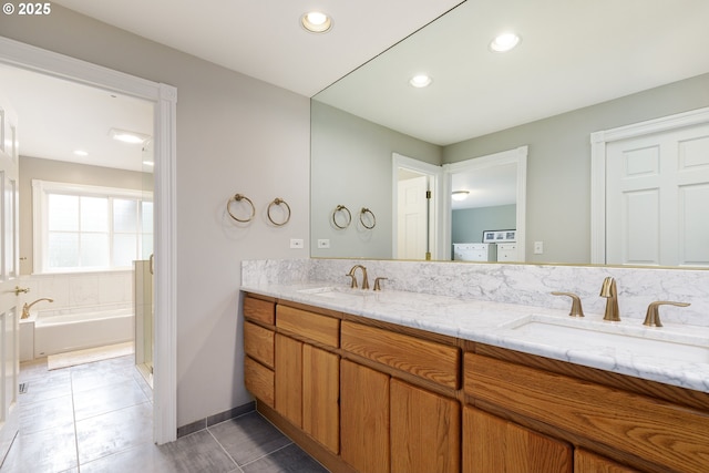 full bath with double vanity, recessed lighting, a sink, and a bath