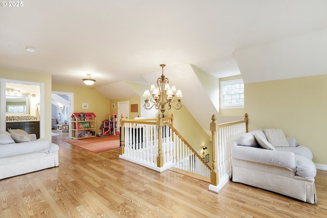 interior space featuring lofted ceiling, light wood finished floors, baseboards, and a chandelier