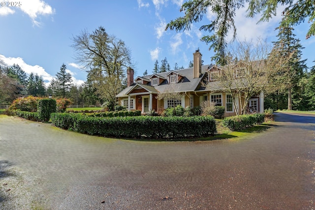 cape cod house with driveway and a chimney