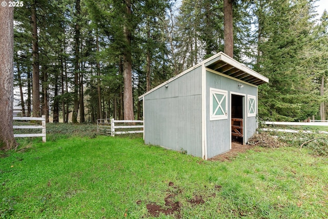 view of outbuilding featuring fence and an outdoor structure