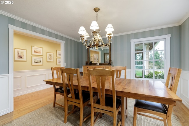 dining space with ornamental molding, light wood finished floors, a wainscoted wall, and wallpapered walls