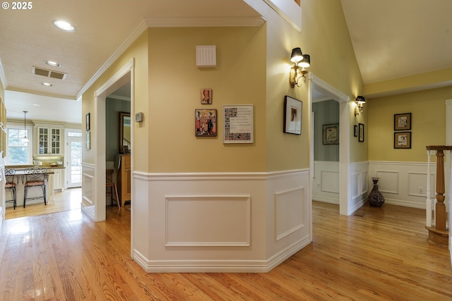 hall with visible vents, a wainscoted wall, crown molding, light wood-style floors, and recessed lighting