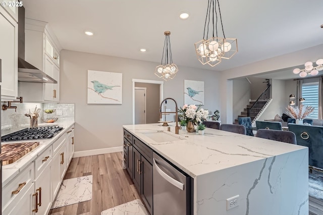 kitchen featuring a sink, backsplash, wall chimney exhaust hood, white cabinets, and dishwasher