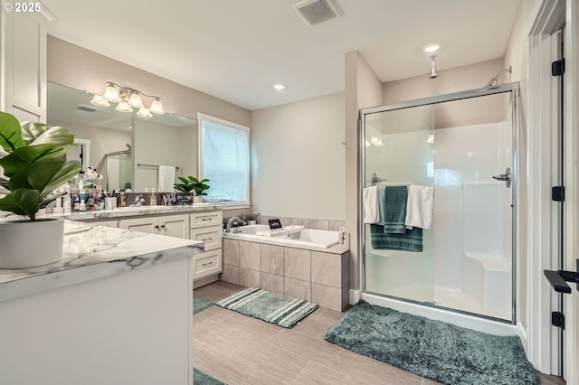 full bath featuring vanity, a shower stall, a garden tub, and visible vents