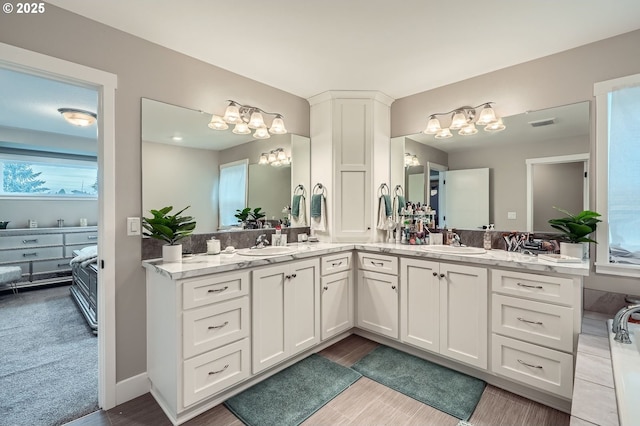 bathroom with double vanity, a notable chandelier, visible vents, and a sink