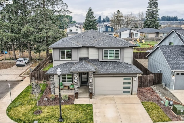 traditional-style house featuring concrete driveway, an attached garage, fence, and a residential view