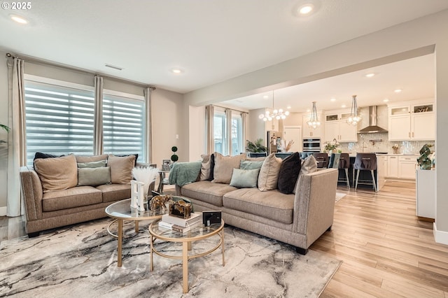 living room with light wood-type flooring, visible vents, an inviting chandelier, and recessed lighting