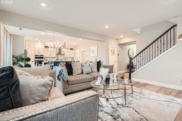 living area featuring stairway, light wood-type flooring, and baseboards