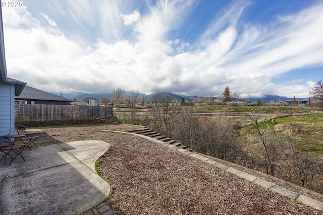 view of yard with a patio area, a mountain view, and fence