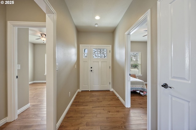 entryway with baseboards, wood-type flooring, and ceiling fan