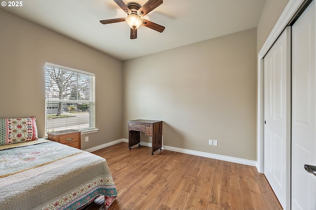 bedroom featuring a closet, baseboards, light wood-style floors, and a ceiling fan