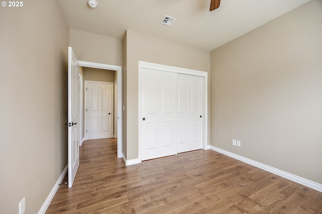 unfurnished bedroom with a closet, baseboards, visible vents, and light wood finished floors