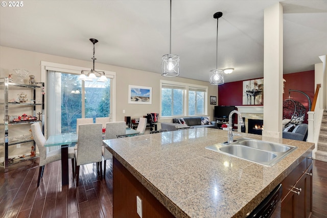 kitchen featuring an island with sink, sink, dark wood-type flooring, and decorative light fixtures