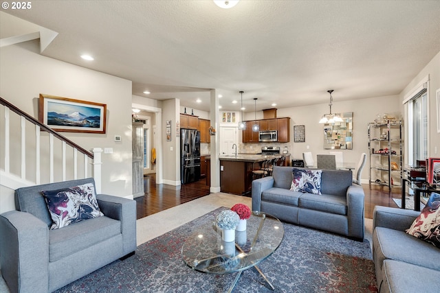 living room featuring an inviting chandelier, sink, dark wood-type flooring, and a textured ceiling