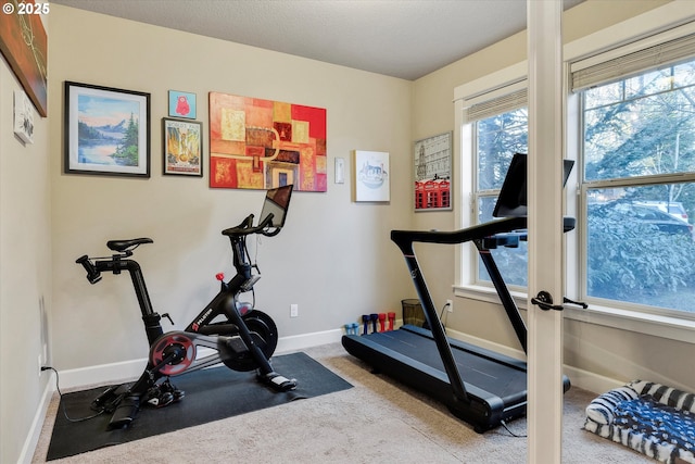 exercise room featuring light colored carpet and a textured ceiling