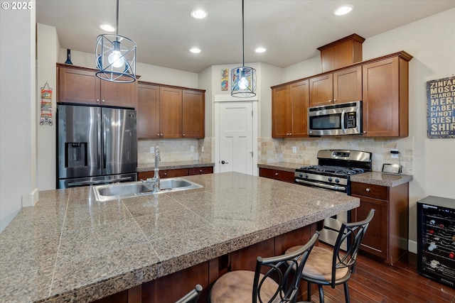 kitchen featuring sink, a breakfast bar area, stainless steel appliances, wine cooler, and decorative light fixtures