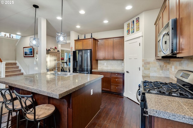 kitchen with sink, decorative light fixtures, appliances with stainless steel finishes, a kitchen breakfast bar, and dark hardwood / wood-style flooring