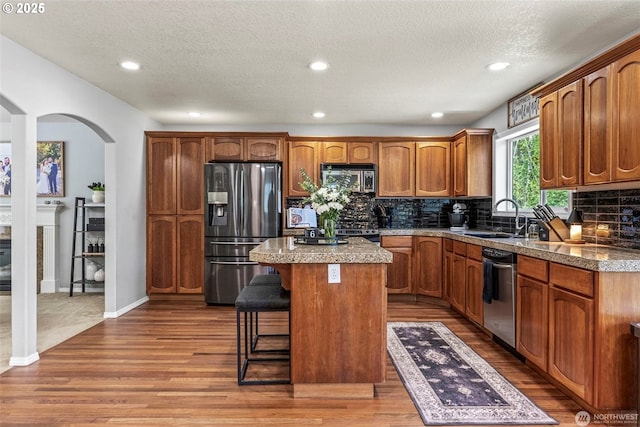 208 Salmonberry Ln, Longview, WA 98632 - kitchen with stainless steel appliances, a sink, wood finished floors, arched walkways, and a textured ceiling