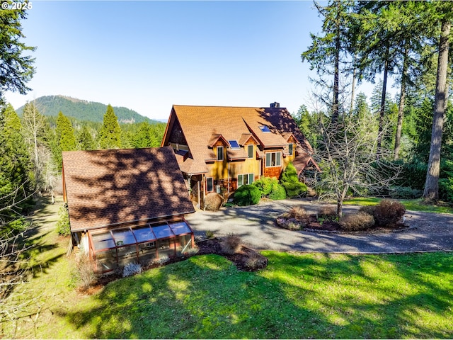 exterior space featuring an outbuilding, a lawn, a chimney, and a mountain view