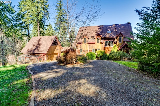 tudor-style house featuring driveway, a front yard, and an outdoor structure