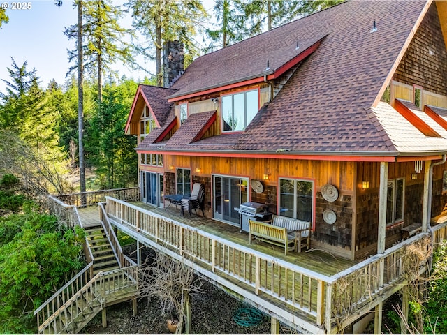 rear view of house with a chimney, stairway, a deck, and roof with shingles