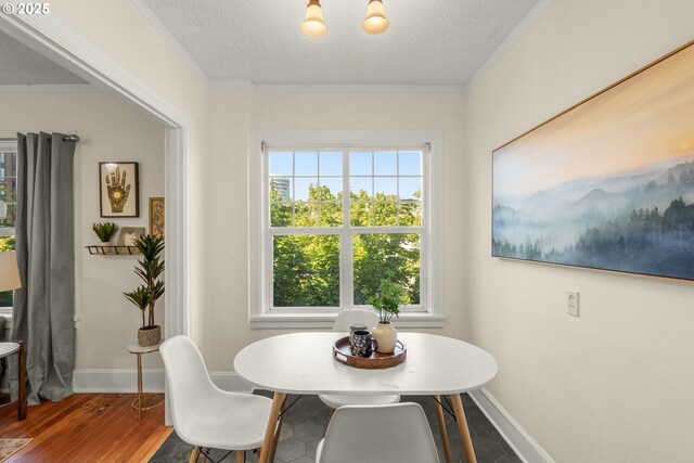 dining area with wood finished floors, baseboards, ornamental molding, and a textured ceiling